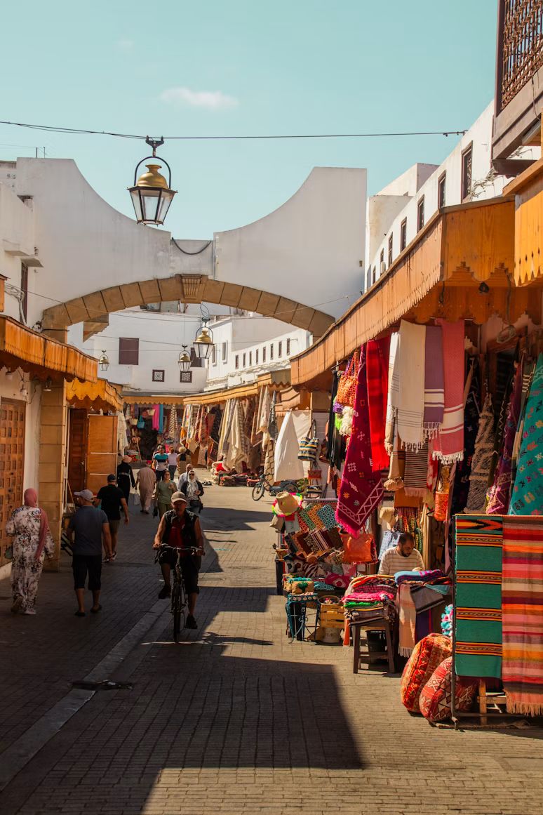 Eine Souk-Straße in Marrakesch mit Teppichen und Passanten